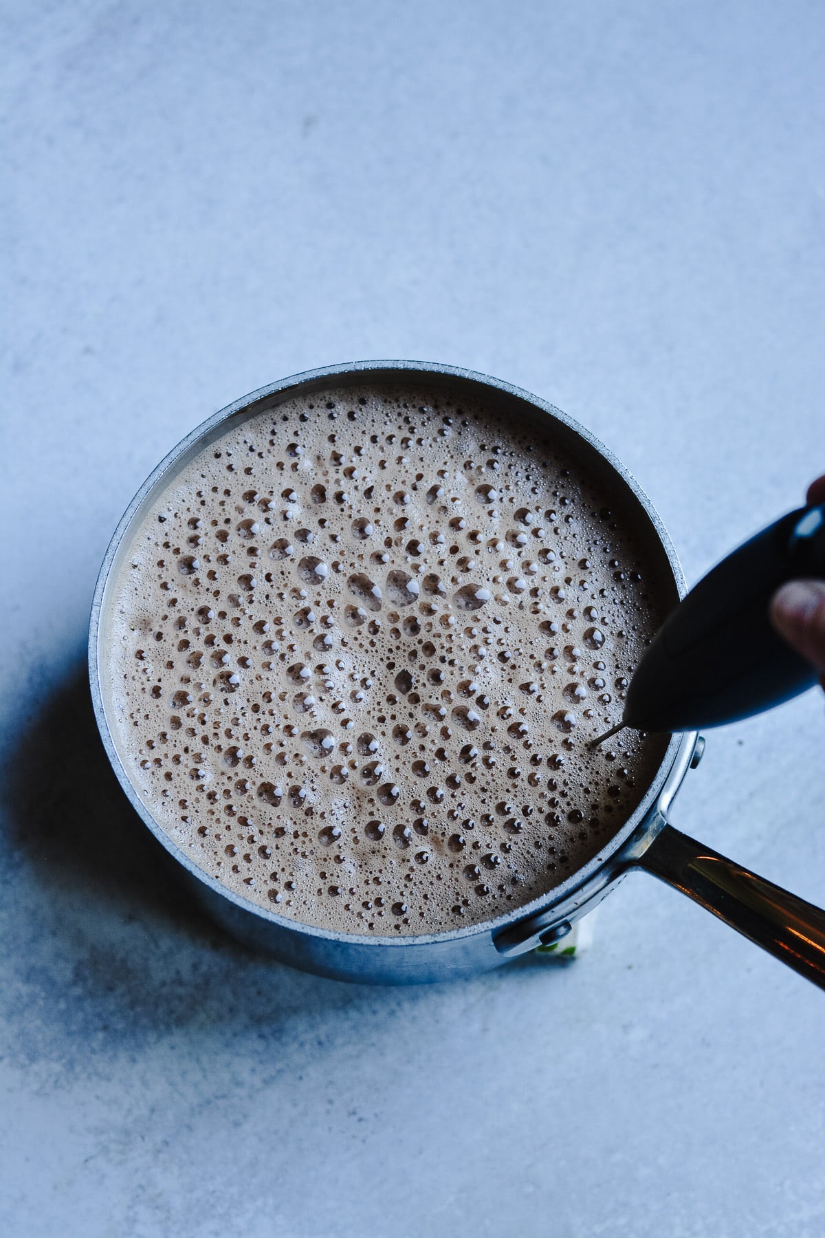 milk frother mixing the hot chocolate in a saucepan.
