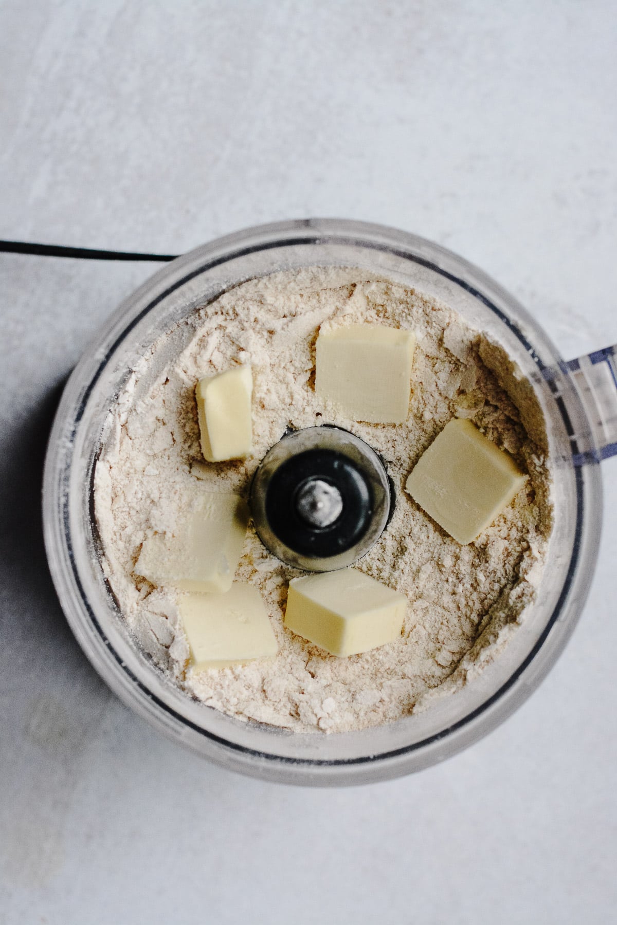 Dry ingredients with butter pads in food processor.