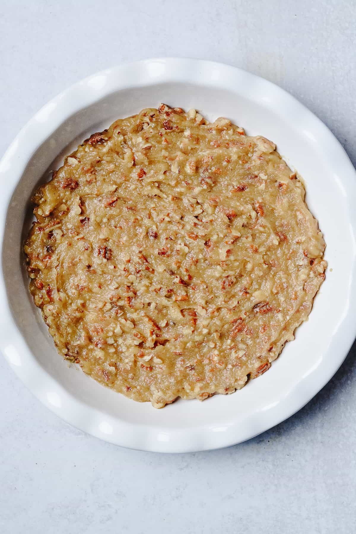 Pecans, butter, sugar and corn syrup spread on bottom of pie plate.