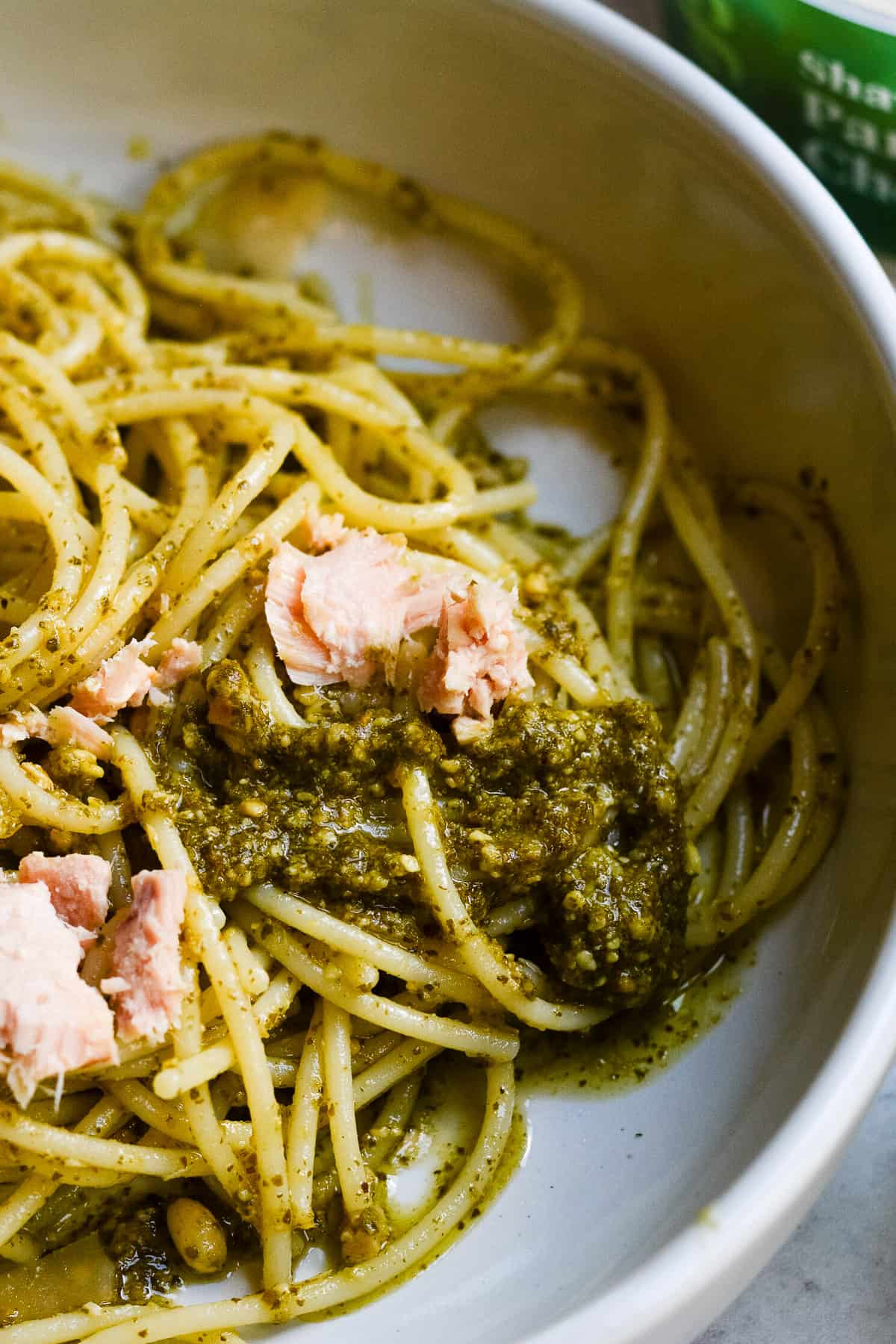 Close up of bowl of pasta with pesto and tuna.