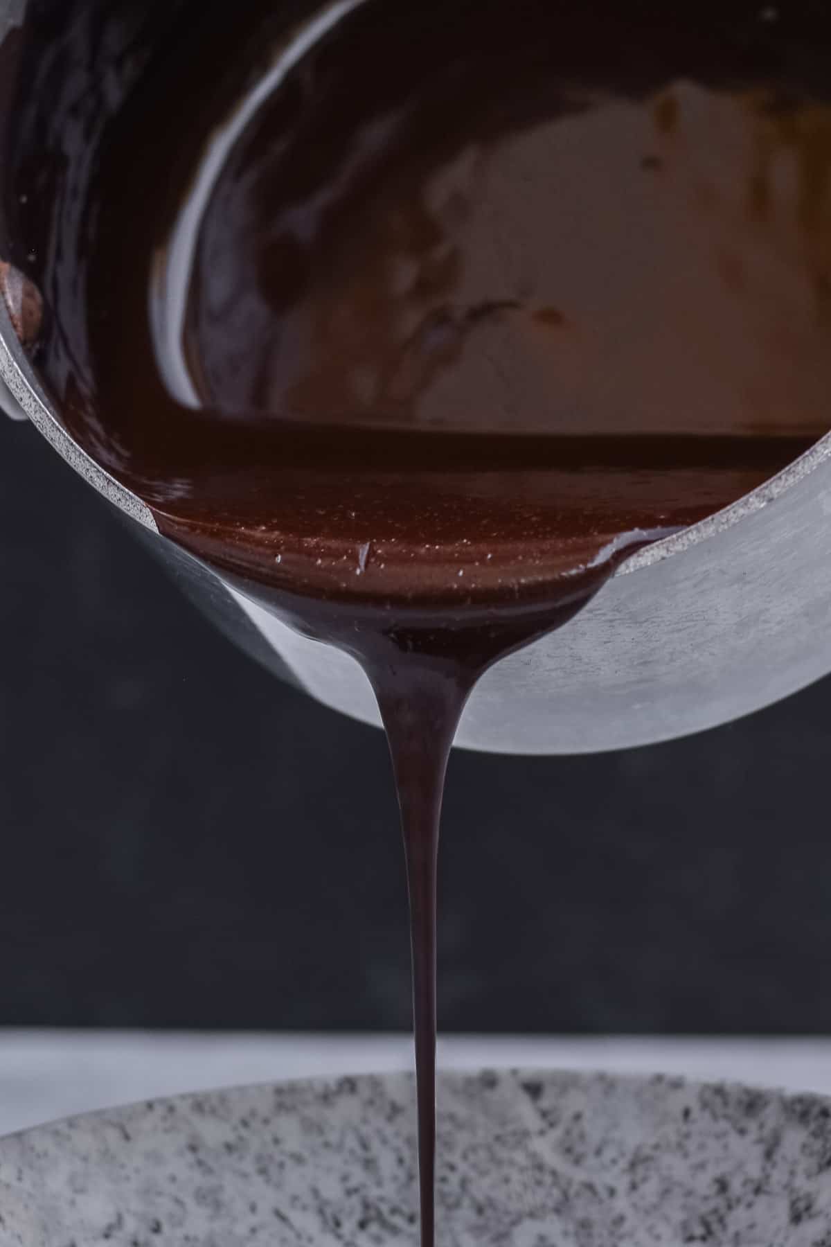 Saucepan pouring chocolate sauce out into a bowl.