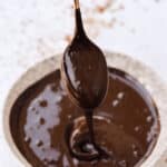 Chocolate sauce dripping off a spoon into a bowl.