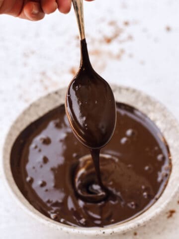 Chocolate sauce dripping off a spoon into a bowl.