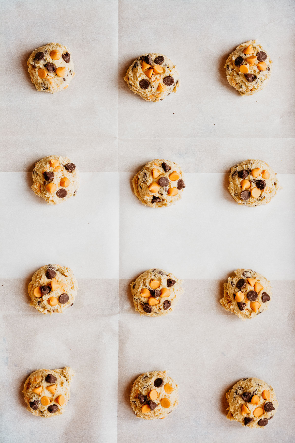 Cookie Dough balls lined up on cookie sheet topped with chocolate chips and butterscotch chips.