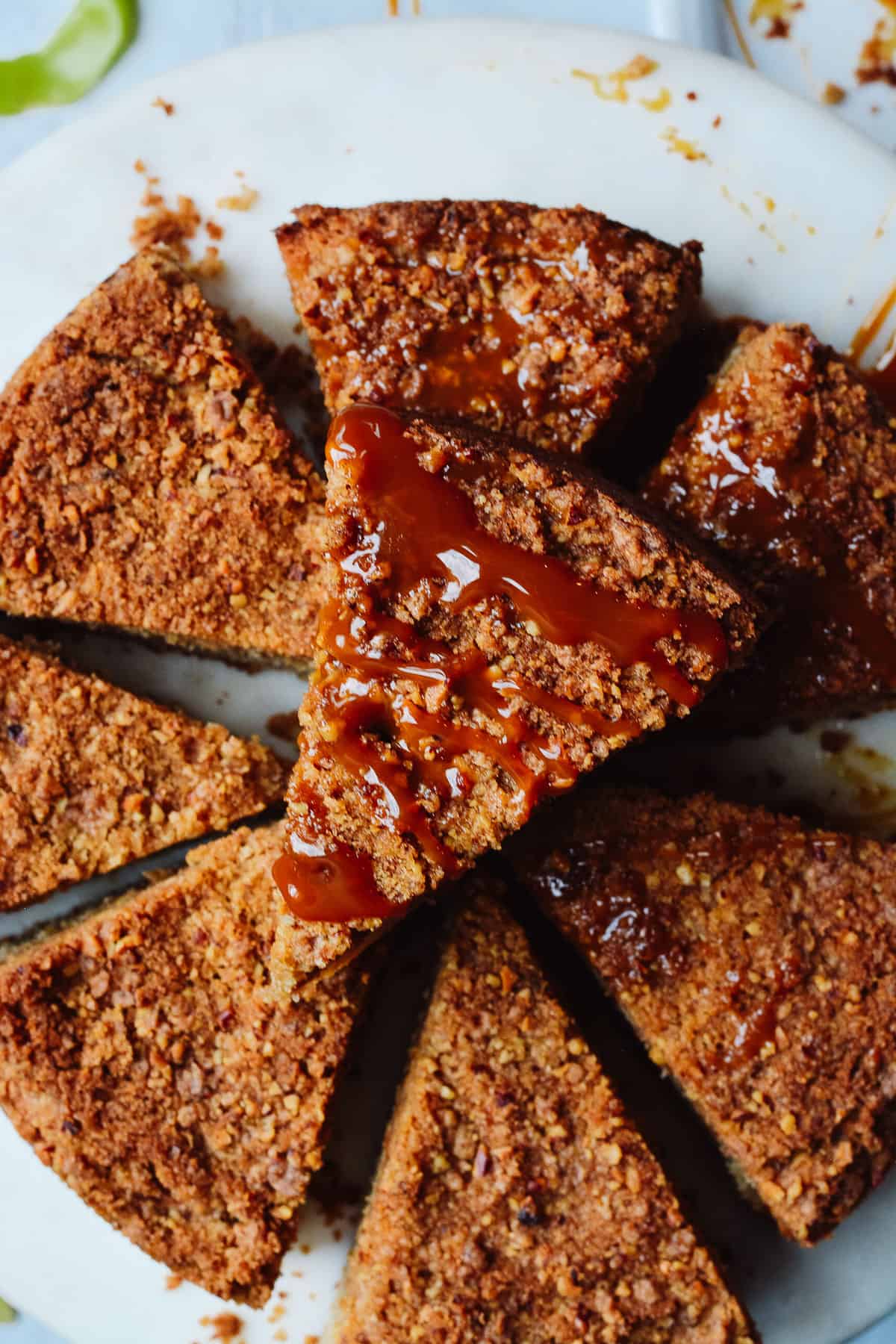 Slices of caramel apple cake arranged on cake plate. Once slice sits on top drizzled with caramel sauce.