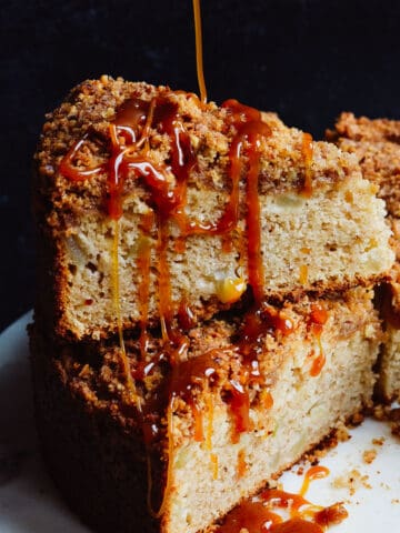 Caramel being poured over slices of apple cake stacked on each other.