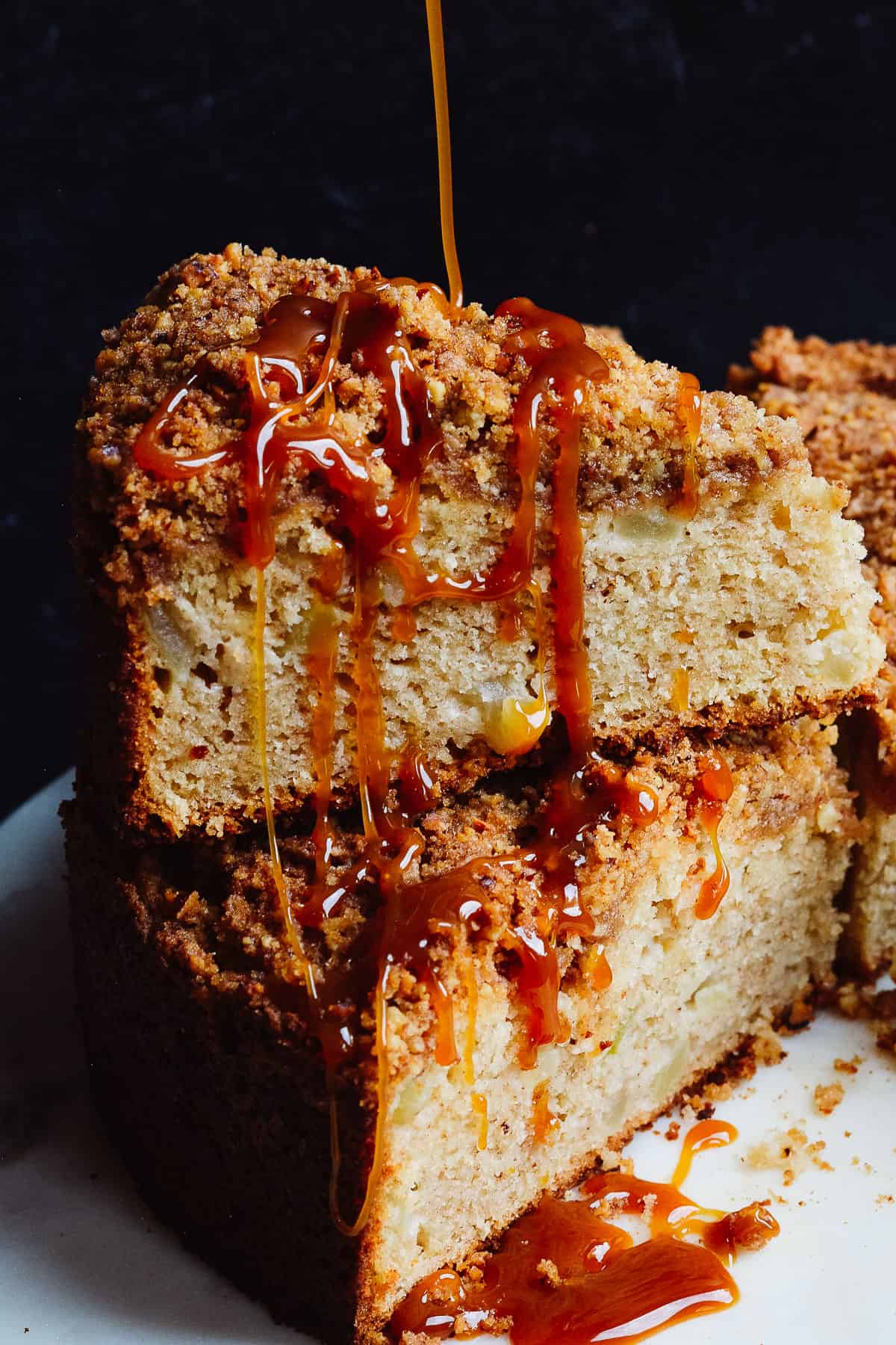 Caramel being poured over slices of apple cake stacked on each other. 