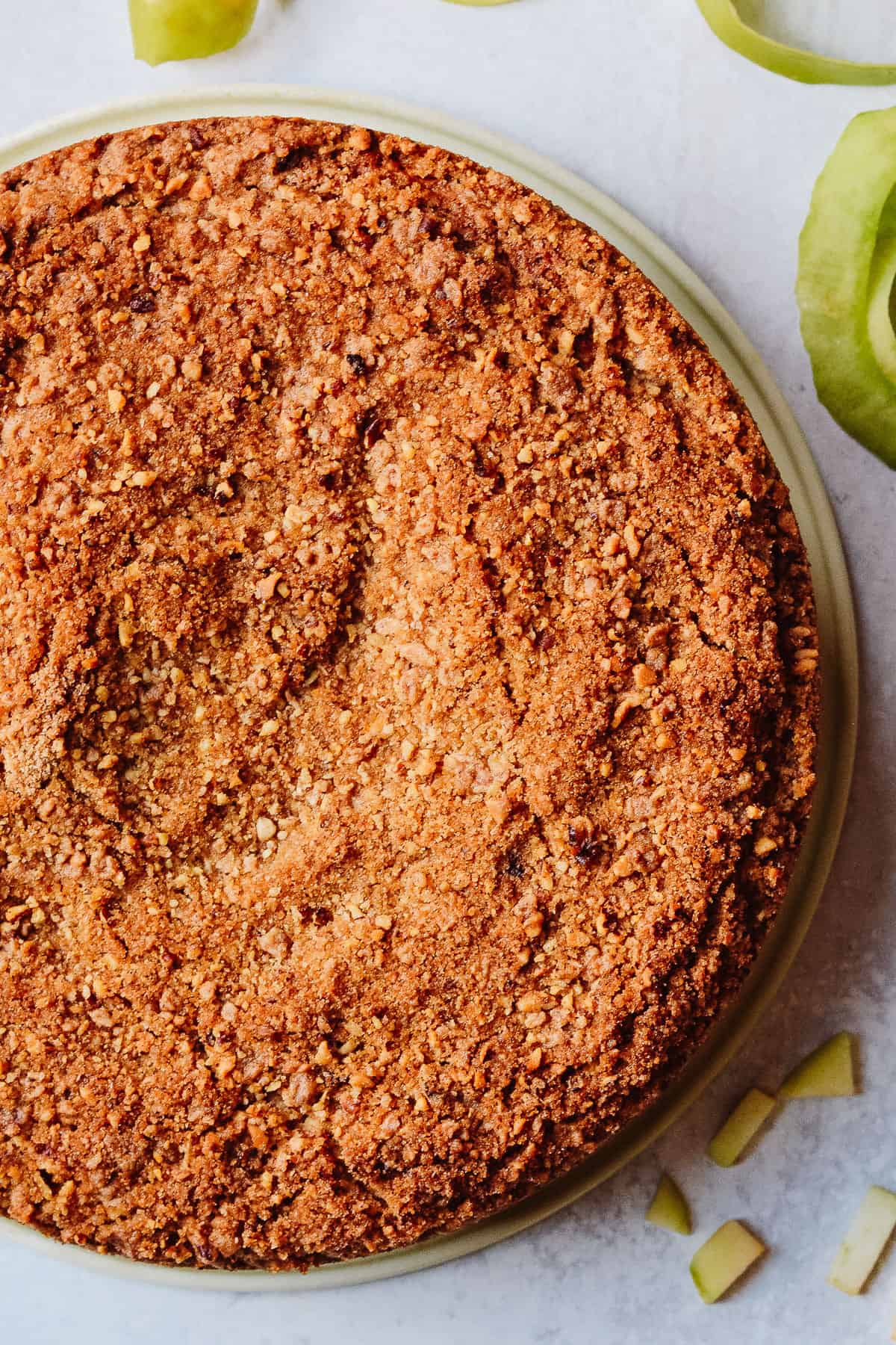 Perfectly baked apple spice cake on marble counter with apple peel around.