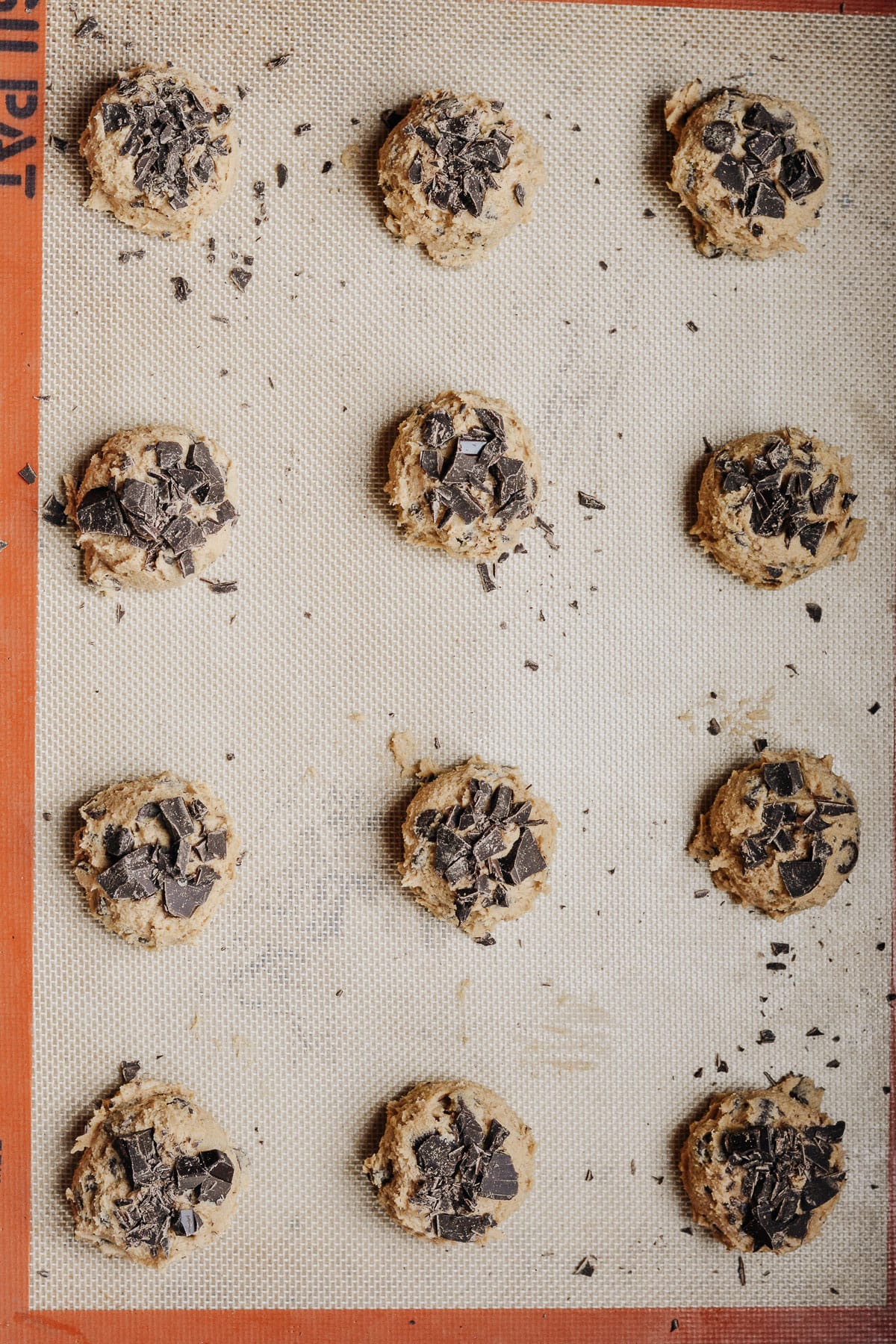 Top down view of cookie dough balls on a baking sheet lined with a silpat mat.